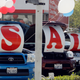 a photo of cars lined up outside a car dealership on a sunny day. four cars have posters hung on their hoods spelling out "sale", and red white and blue balloons are tied to the cars